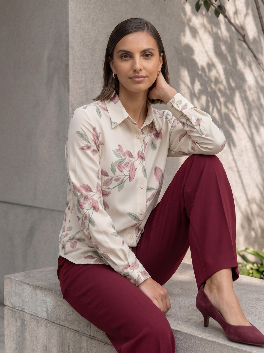 Close-up of a woman seated in a cream leaf print button-down workwear shirt