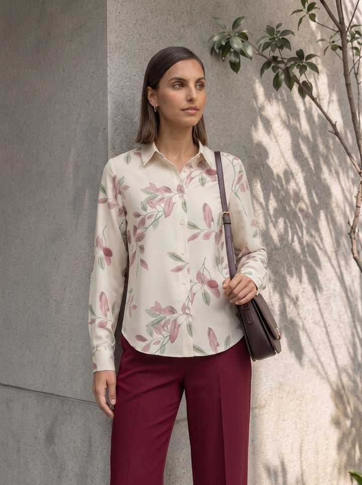 Woman wearing a cream patterned long-sleeve shirt paired with a brown shoulder bag